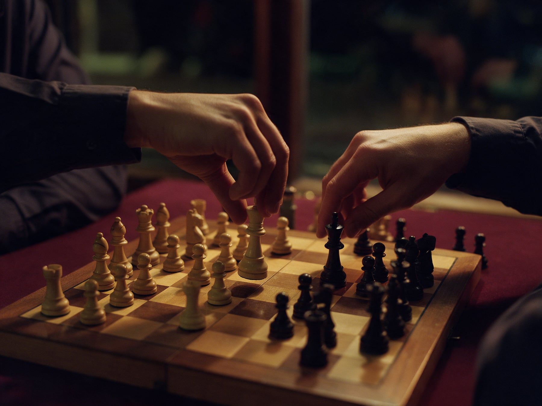 Deux mains jouent aux échecs, l’une déplace la reine blanche